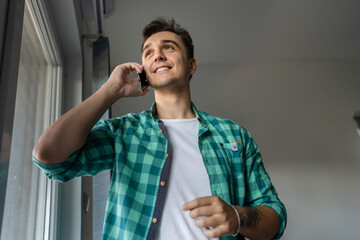 One man caucasian male standing by the window using mobile phone talk