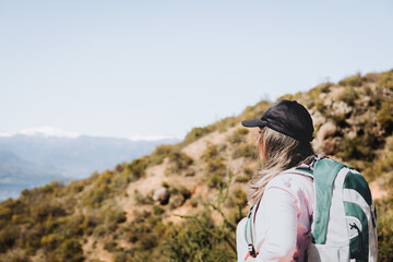 Rear view young latin plus size woman with backpack on, contemplating view from the top of a hill