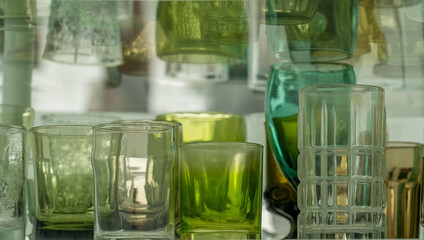 Assortment of various shapes and size green cups and glasses on a shelf