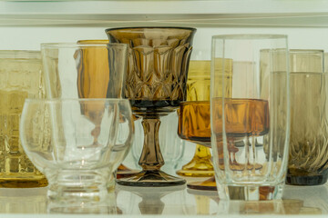 Assortment of various shapes and size yellow cups and glasses on a shelf