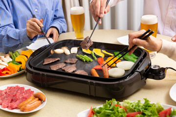 ビールを飲みながら焼肉を食べる家族