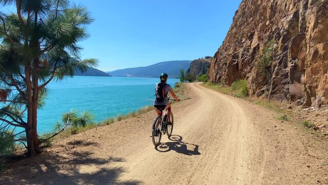 Woman riding bike along beautiful lake side trail
