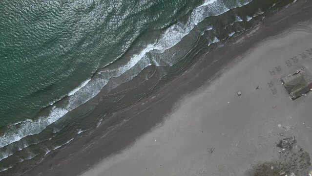 Drone with camera takes off over the Great Beach in Ulcinj, washed by waves of dark turquoise Adriatic Sea. Resort infrastructure on deserted sandy coast in the off-season.