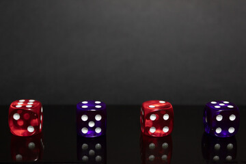 Four dice on a reflective black surface and a dark background