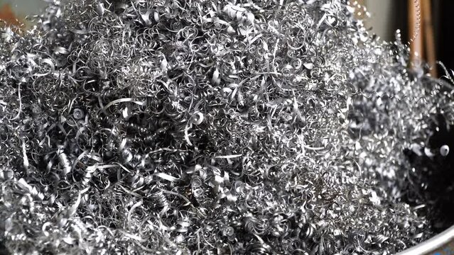 Steel scrap materials recycling. Aluminum chip waste after machining metal parts on a cnc lathe. Closeup twisted spiral steel shavings. Small roughness sharpness,