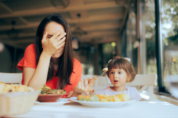 Mother Exasperated by Picky Eating Daughter in a Restaurant. Disobedient toddler girl being fussy...