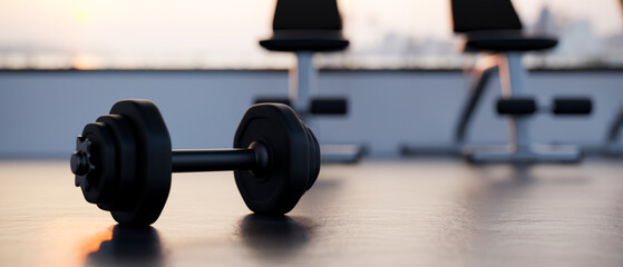 Dumbbell is on a gym floor over blurred modern fitness gym in the background.