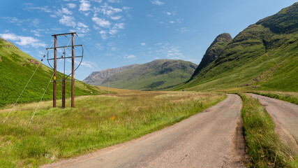 Telephone poles and cable leading along the valley of Glen Coe,Scottlsh Highlands,United Kingdom. - obrazy, fototapety, plakaty