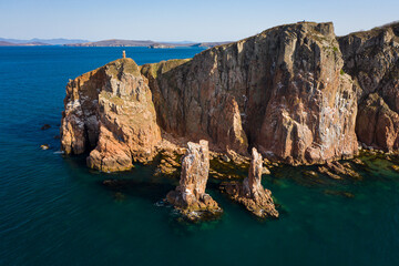 Beautiful high vertical cliffs on the sea coast at dawn. Two sea stacks, vertical columns in the...