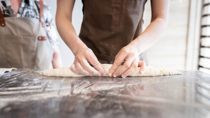 The process of making traditional French baguettes. Forming a blank from the dough. Front view.