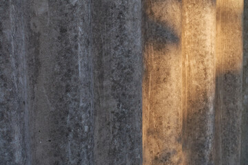 Old used slate covered with mold stands against the wall. The sun shines on the right half of the slate.