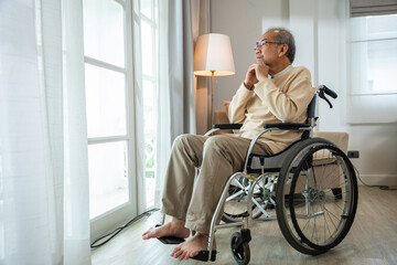 Asian senior man disabled sitting alone in wheelchair looking through window at hospital, lonely...