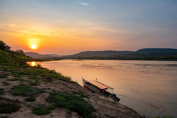 Long-tailed boat is anchored on the shore in the Mekong river during sunset or sunrise at Ubon Ratchathani province unseen Thailand.