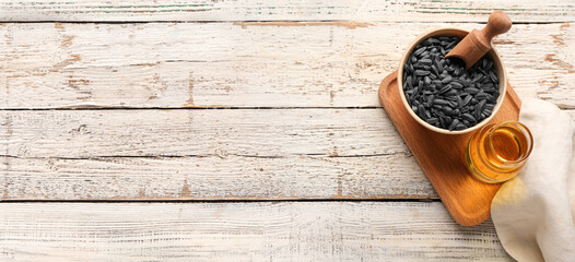 Sunflower oil and seeds on light wooden background with space for text, top view