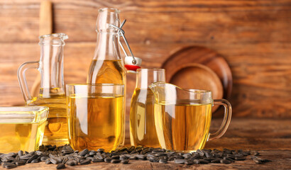 Glassware of sunflower oil and seeds on wooden background