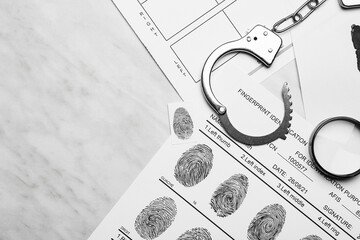 Paper sheets with finger prints and handcuffs on white background