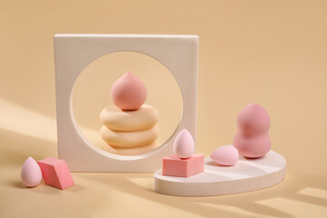Pink makeup sponges with decor on beige background