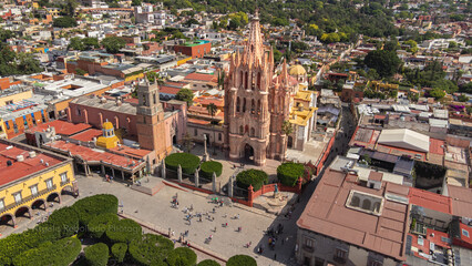 Fototapeta premium the church Parroquia Archangel Jardin Town Square Night Tree Decoraciones San Miguel de Allende, México. Parroaquia. Night and morning light in a drone view.
