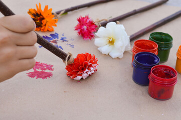 Close-up of children's hands that create a drawing using a flower by poking. What to do with children in kindergarten or school camp in the summer.