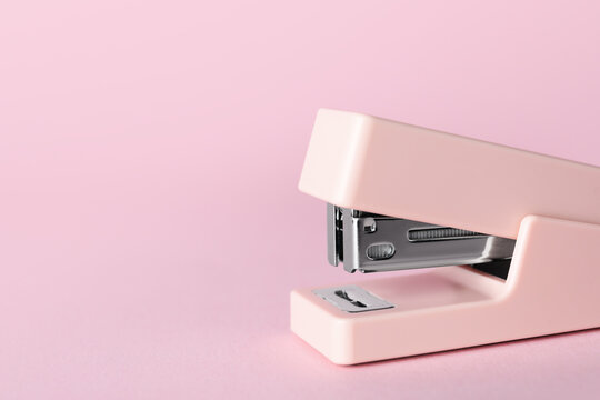 Pink stapler on color background