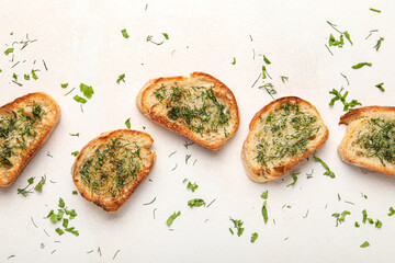 Slices of delicious toasted garlic bread with greens on light background