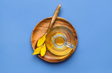 Wooden plate with decanter of sunflower oil on blue background