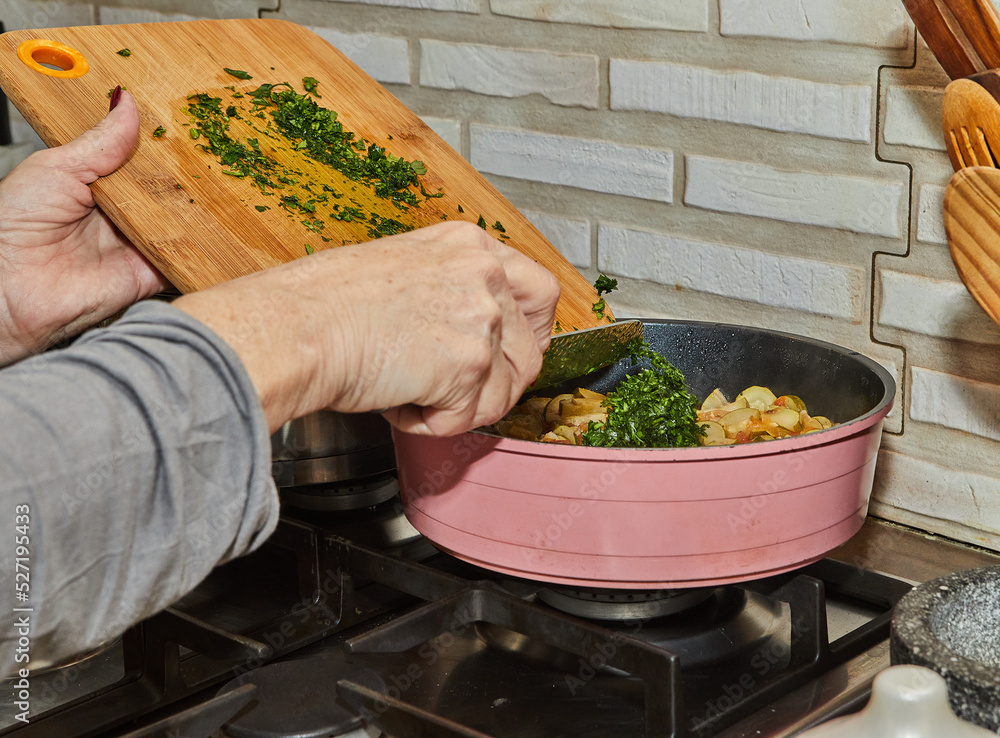 Wall mural Chef throws parsley to Zucchini with carrots are fried in frying pan on gas stove