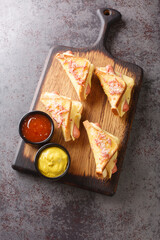 Fried crispy bread with sausage and melted cheese closeup in the wooden board on the table. Vertical top view from above