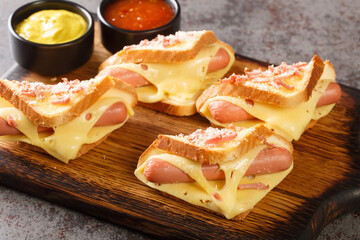 Hot sandwich with Vienna sausages and melted cheese served with ketchup and mustard close-up on a...
