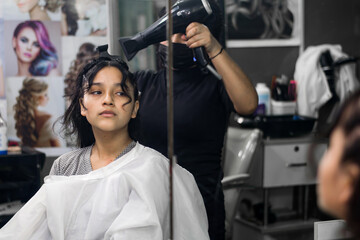 Young woman getting makeup and hair done in a professional spa or hair salon. Blow-dry styling