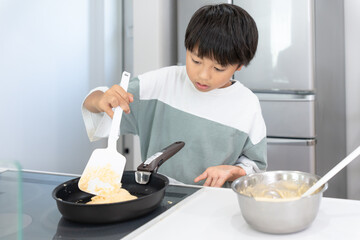 自宅のキッチンで料理をしているアジア人の男の子