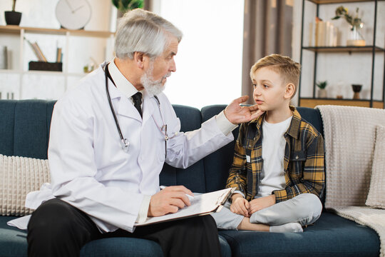 Mature doctor groping checking pain and swelling in the neck sore throat and cough thyroid nodule inflammation of the lymph nodes tonsillitis of sick male patient boy during home visit