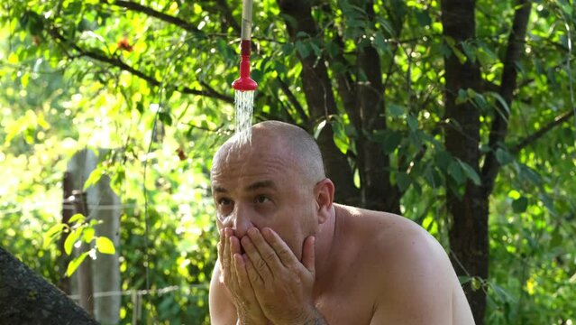 Man aching from extreme heat escapes high temperature under summer shower