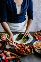 mexican woman hands preparing and cooking chiles en nogada recipe with Poblano chili and ingredients, traditional dish in Puebla Mexico	