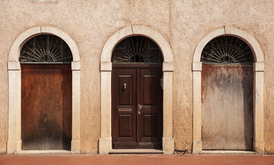 Stone wall with three arched doorways. Vintage wooden doors