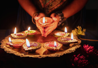 Diwali Festival of lights celebration. Diya lamp in woman hands, close up