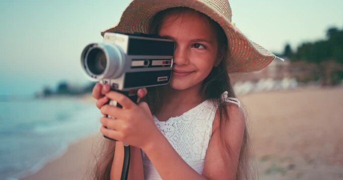 Girl with white dress and long hair making pictures and video with old vintage camera of beautiful sea sunrise and beach