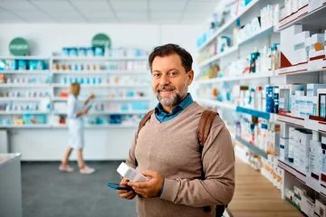 Papier Peint photo Lavable Pharmacie Client masculin faisant ses courses en pharmacie et regardant la caméra.