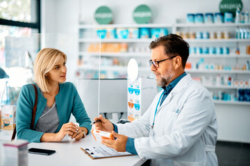 Female customer talks to pharmacist while buying medicine in drugstore.