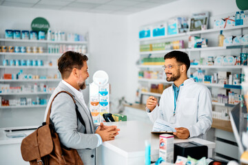 Obraz premium Happy pharmacist advising male customer in pharmacy.