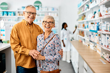 Portrait of happy senior couple in pharmacy looking at camera.