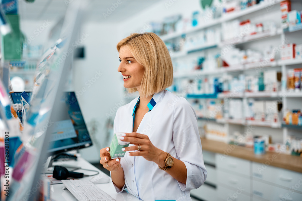 Wall mural Smiling pharmacist gives advice about medicine while working in pharmacy.