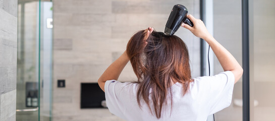 young woman using hair dryer at home or hotel. Hairstyles and lifestyle concepts