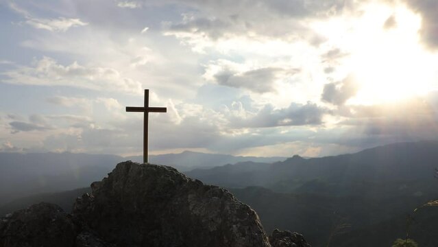 Christian cross on top rock mountain on the colorful sky background. Christian background concept