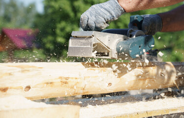 a carpenter works with an electric pipe on a sunny day