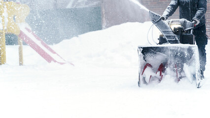 a janitor on a snowplow removes snow in the courtyard of a residential building