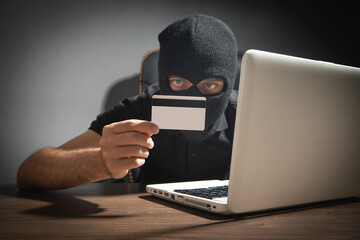 Hacker with credit card and laptop computer. Cyber crime