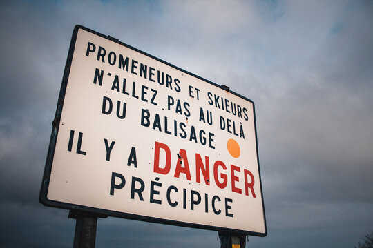 Mountain warning sign translating danger for hikers cliff drop in french, in Ballon d'Alsace, Vosges, France