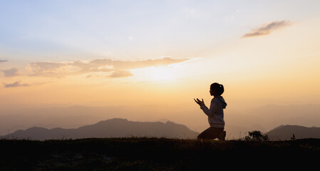 Silhouette of a woman praying outside at beautiful landscape at the top of the mountain, Copy space of man rise hand up on top of mountain and sunset sky abstract background. - obrazy, fototapety, plakaty
