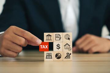 Businessman Hand holding Wooden blocks with the word tax and tax icons.Financial research,...